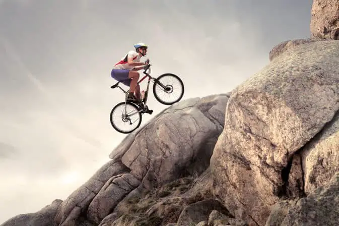 Photo of a cycling biking uphill in a big boulder. How to Bike Uphill Without Getting Tired.